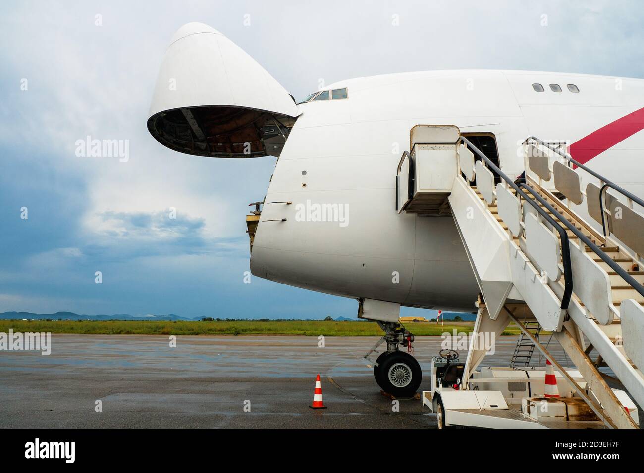 Un avion de transport Jumbo Jet avec un large nez ouvert porte de chargement en attente à une rampe de chargement pour un chargeur haut à décharger Banque D'Images