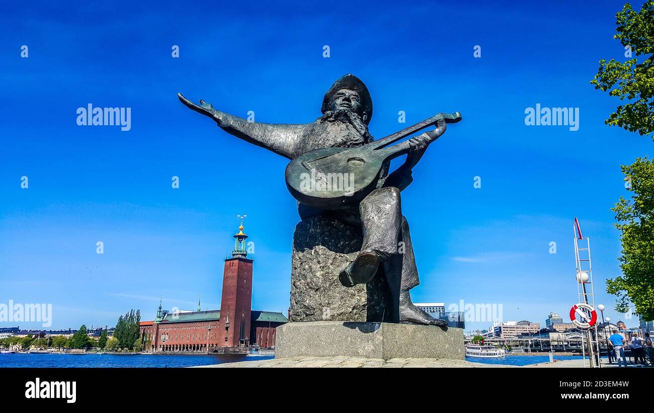 Monument au musicien suédois et troubadour Evert Taube sur fond de l'hôtel de ville de Stockholm. Stockholm, Suède Banque D'Images