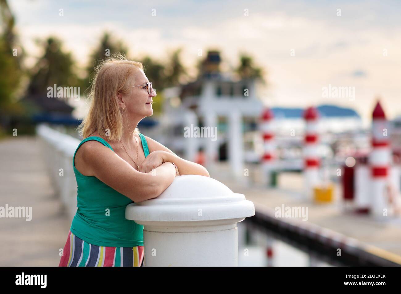 Femme âgée regardant le yacht et le bateau dans le port. Sport de yachting pour la famille. Lady marchant dans un complexe tropical pendant les vacances d'été. Vacances à la mer. Banque D'Images