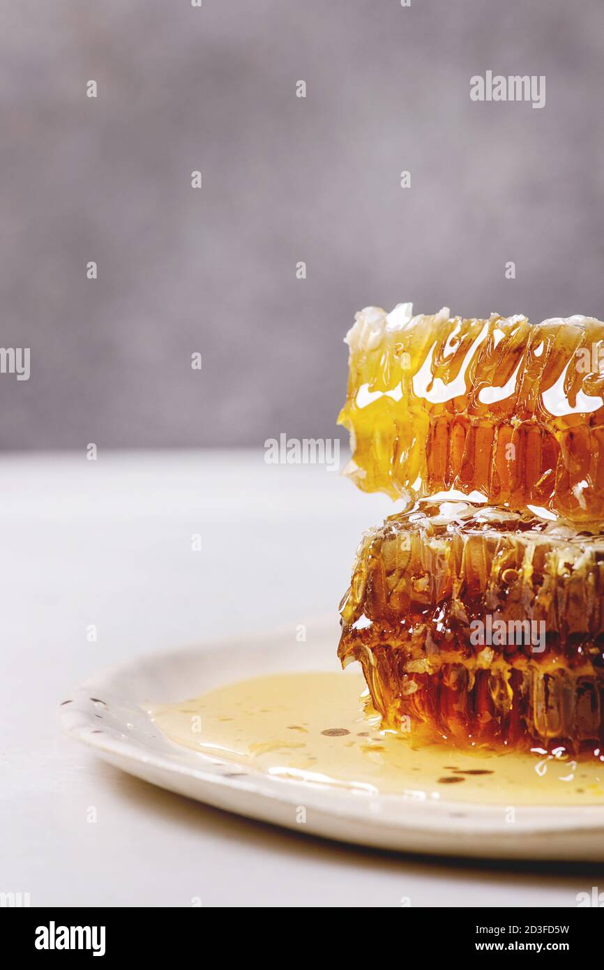 Pile de miel en rayons de miel dans la plaque en céramique sur table de marbre blanc. Banque D'Images