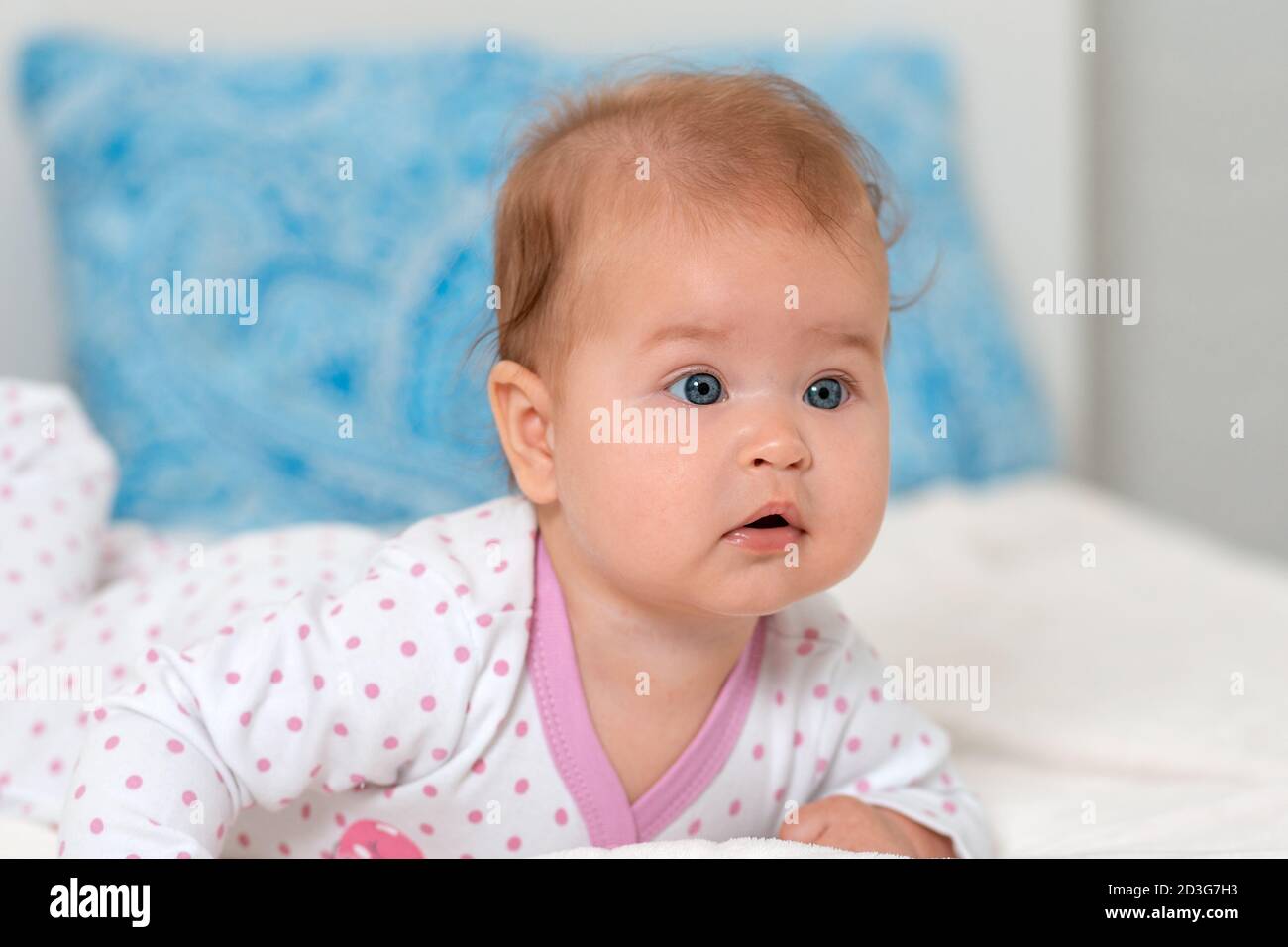 Portrait rapproché d'un bébé caucasien allongé sur le lit. Oreiller sur l'arrière-plan. Banque D'Images