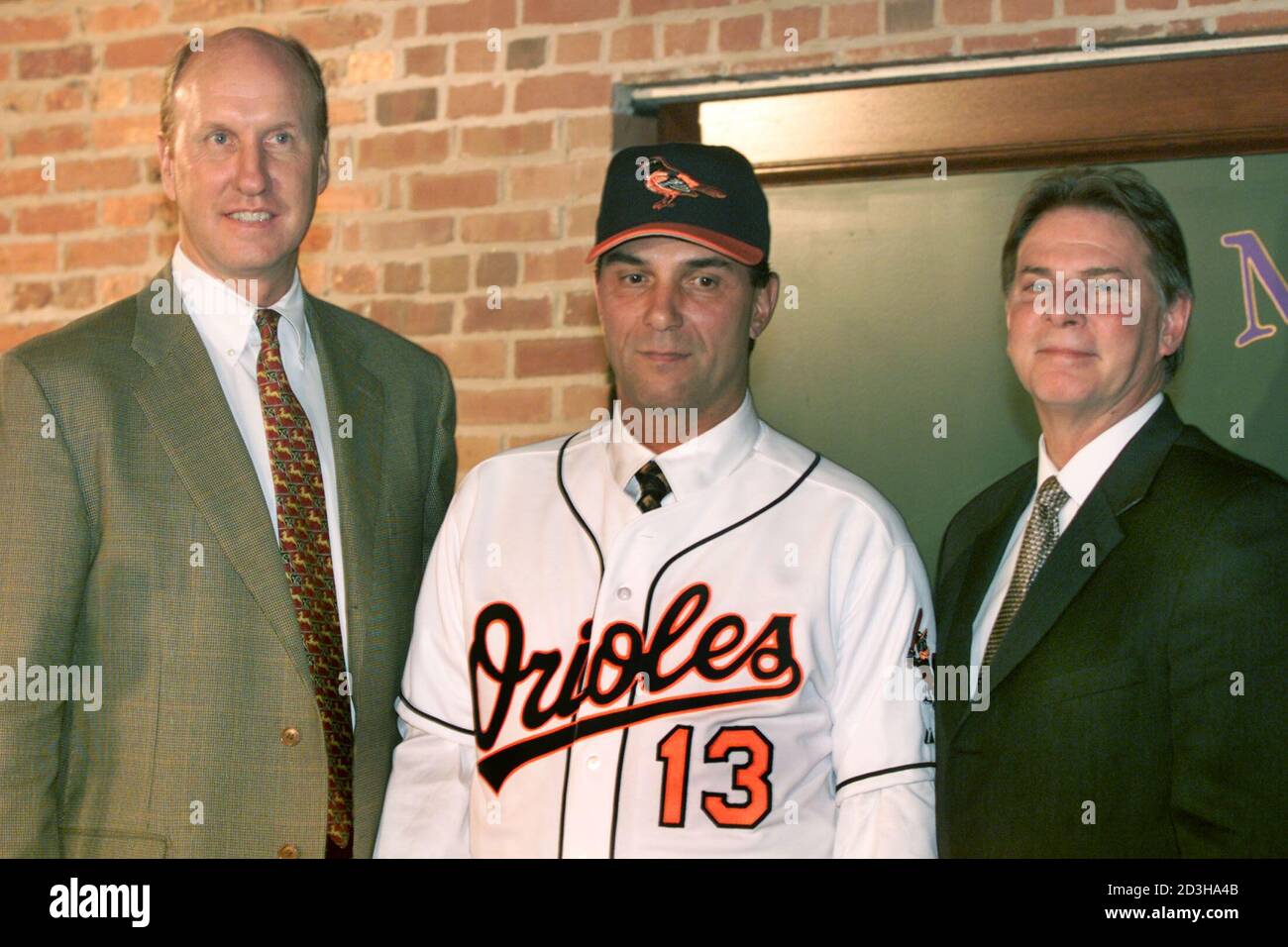 Lee Mazzilli (C) porte une casquette et un uniforme Baltimore Orioles entre  Jim Beattie (L), vice-président exécutif des opérations de baseball d' Orioles, et Mike Flanagan, vice-président des opérations de baseball après  une