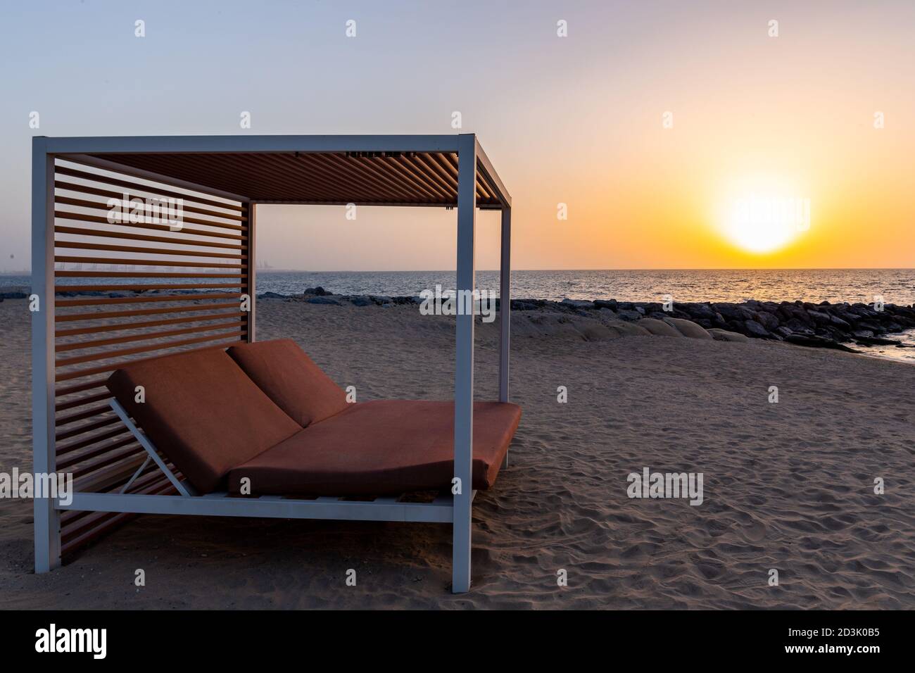 Lit double vide sur la plage de sable de Dubaï, avec coucher de soleil  orange en arrière-plan et mer calme Photo Stock - Alamy