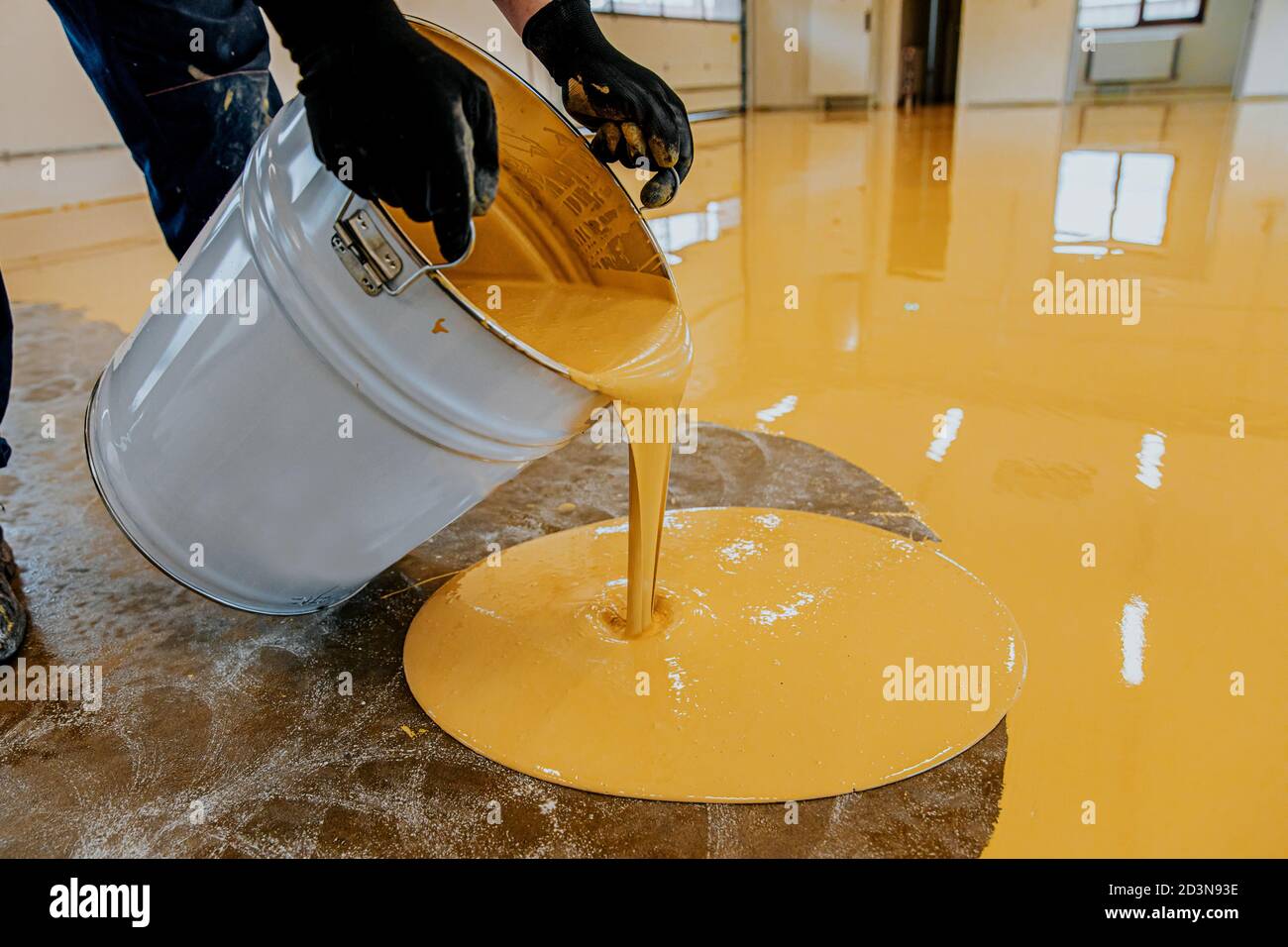 Un travailleur de la construction applique de la résine époxy dans un hall industriel Banque D'Images