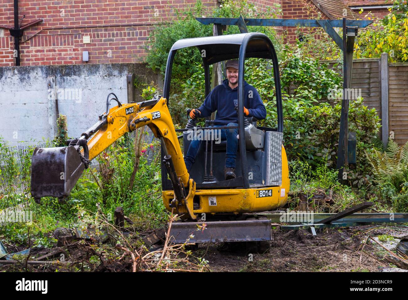 Travaux de déstockage et de rénovation du jardin en octobre à Bournemouth, Dorset, Royaume-Uni - travailleur exploitant la mini pelle hydraulique JCB Banque D'Images