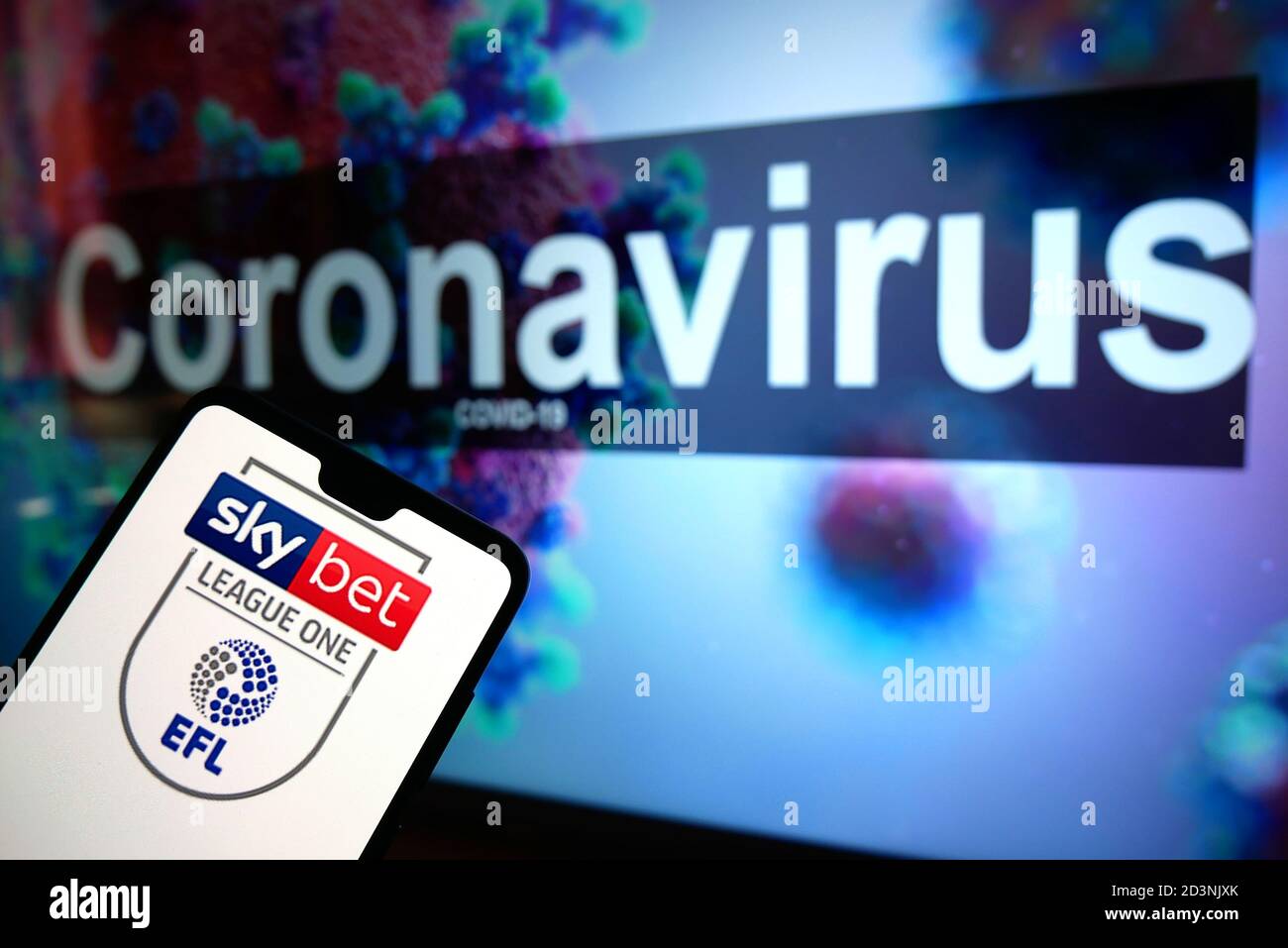 Le logo EFL Sky Bet League One est affiché sur Un téléphone portable avec un modèle d'illustration du coronavirus affiché sur un moniteur Banque D'Images