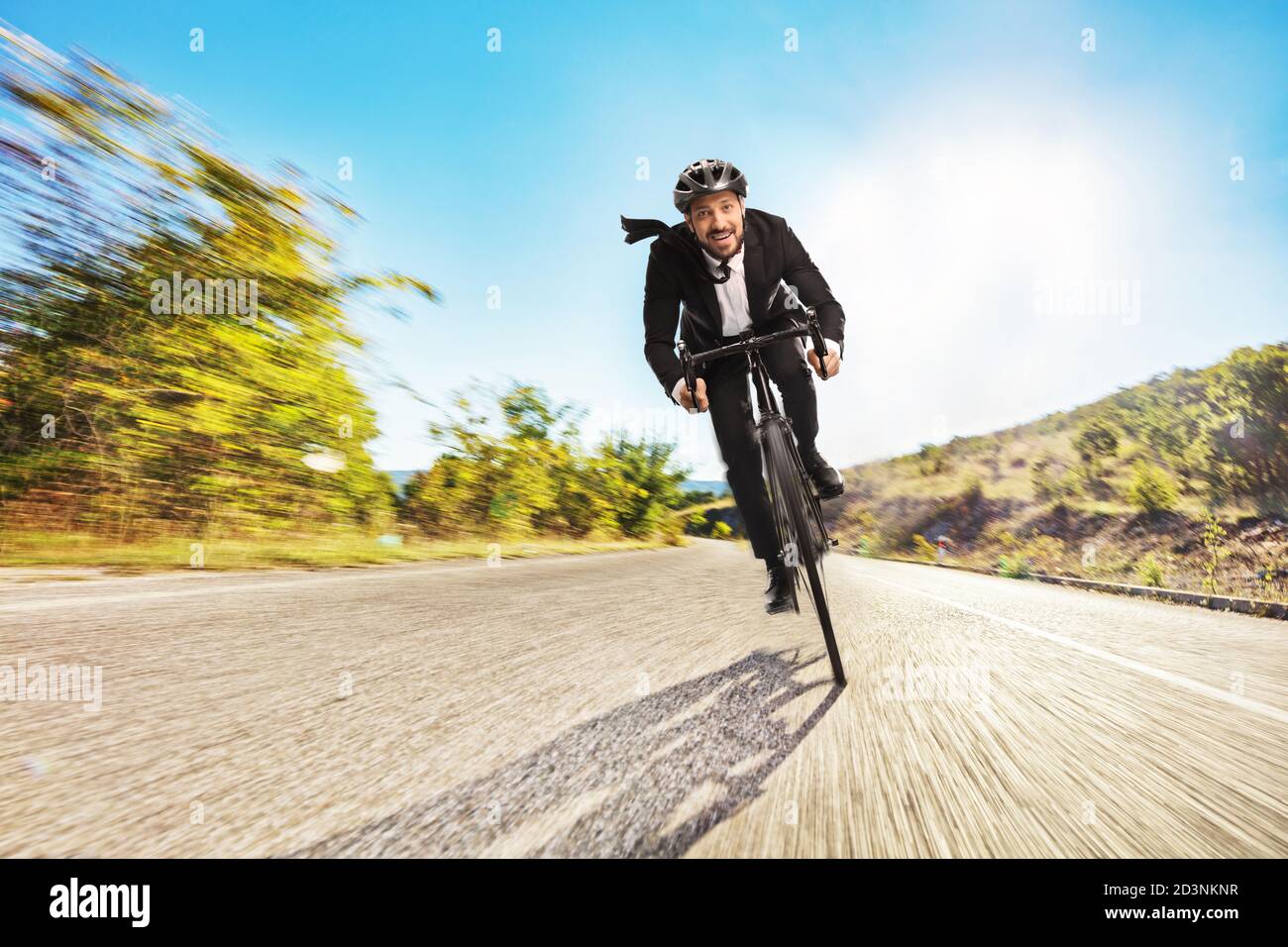 Jeune homme en costume à vélo sur un route ouverte Banque D'Images