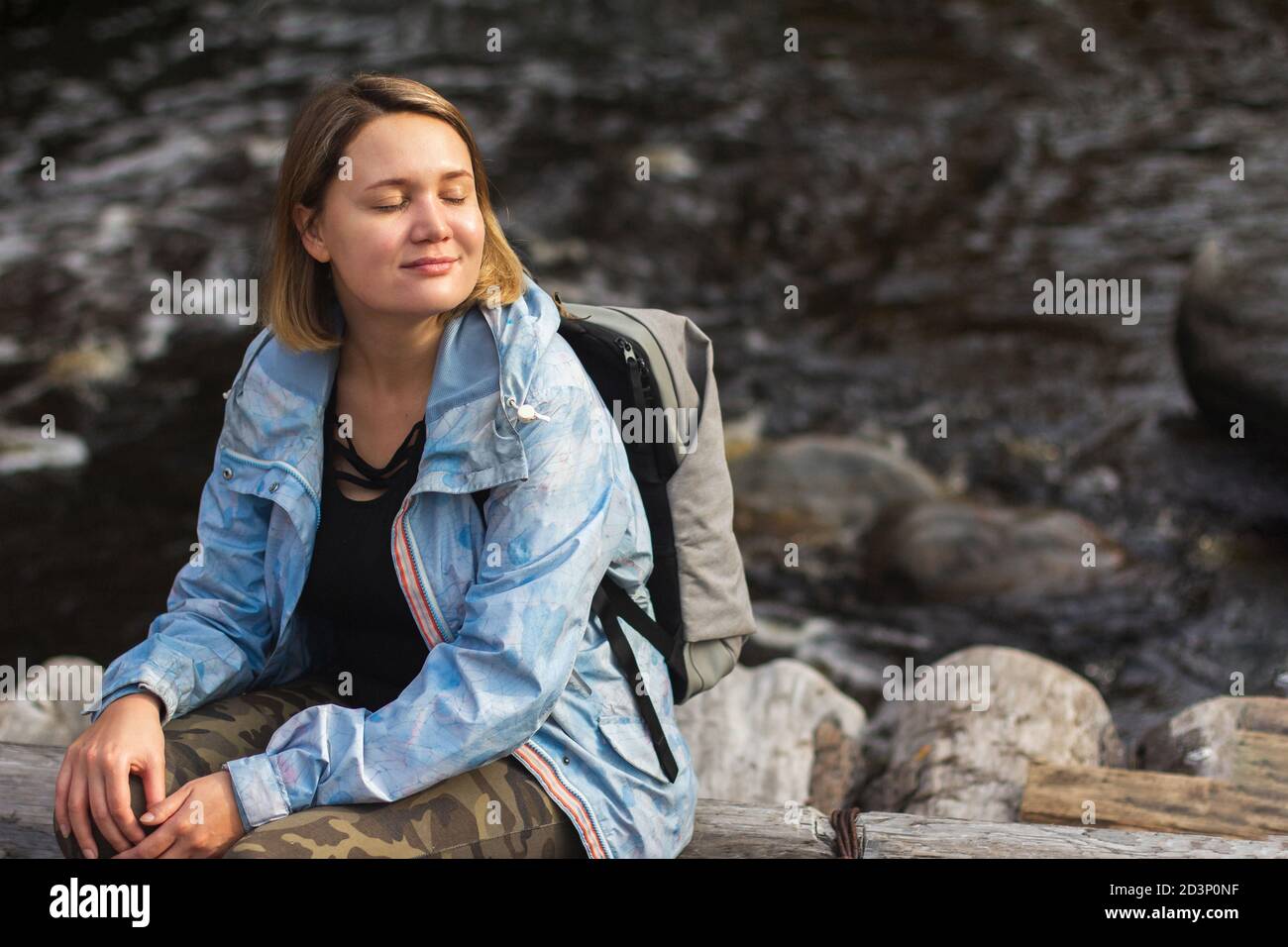 Belle jeune femme repose au bord de la rivière sur une randonnée. Banque D'Images