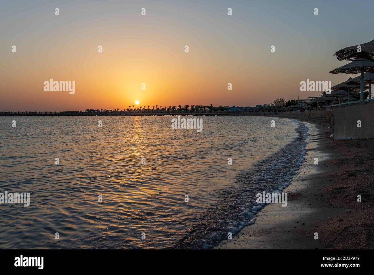 Lever de soleil sur la plage avec parasol surplombant la mer Rouge à Hurghada, Égypte Banque D'Images