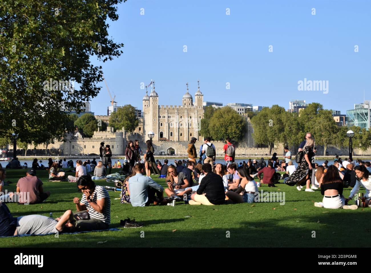 Personnes assises dans le parc Potters Fields avec la Tour de Londres en arrière-plan Banque D'Images