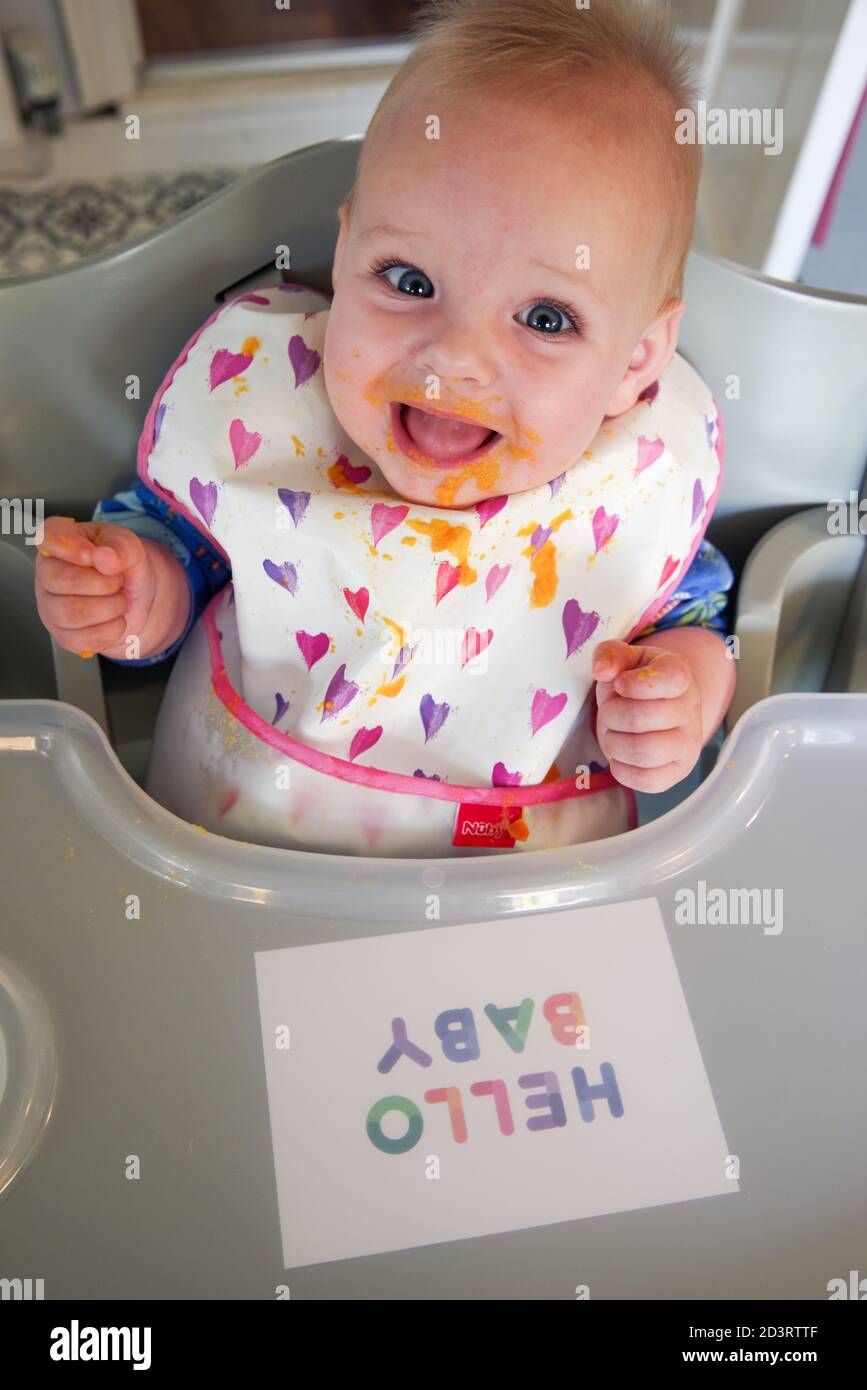 Sourire bébé de 6 mois couvert de purée de carottes Banque D'Images