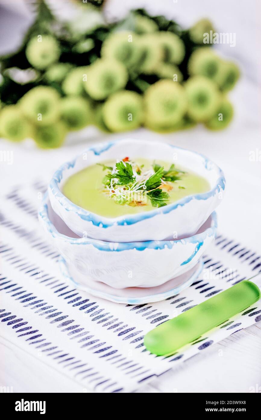 Soupe maison à la crème avec pois verts, feuilles de persil et germes de luzerne sur fond blanc Banque D'Images Soupe maison à la crème avec pois verts, feuilles de persil et germes de luzerne sur fond blanc Banque D'Images