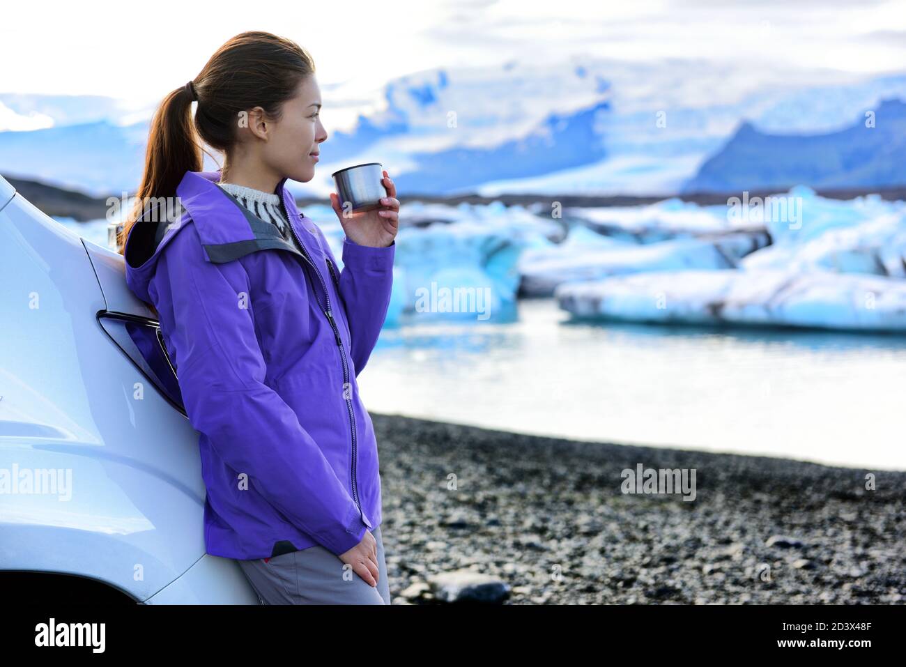 Camping camping-car. Femme buvant un café le matin devant le camping-car tout en conduisant une camionnette de camping sur la route de l'Islande. Chauffeur touristique asiatique Banque D'Images