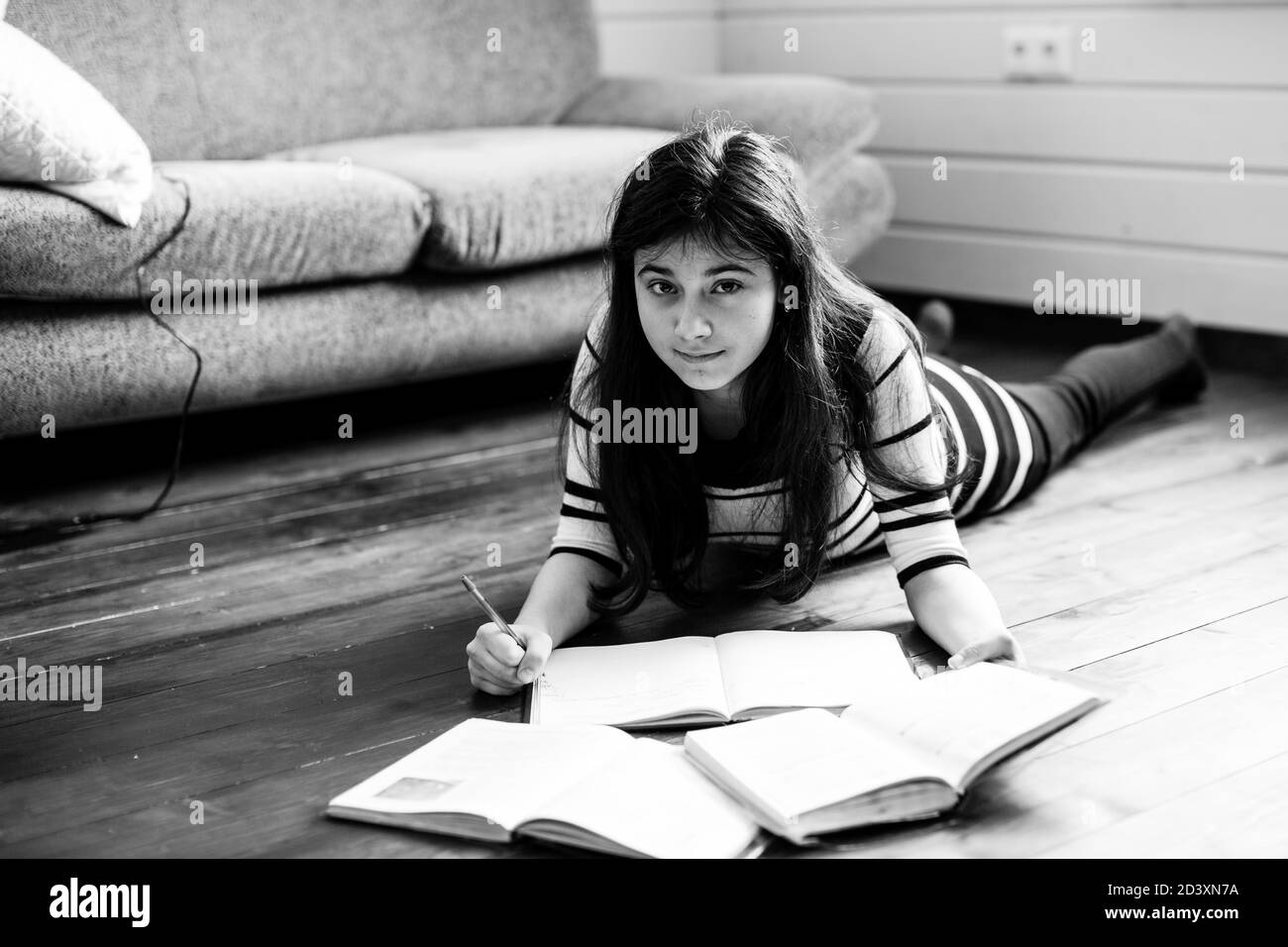 Teengirl faisant ses devoirs à l'étage de la chambre. Photographie en noir et blanc. Banque D'Images