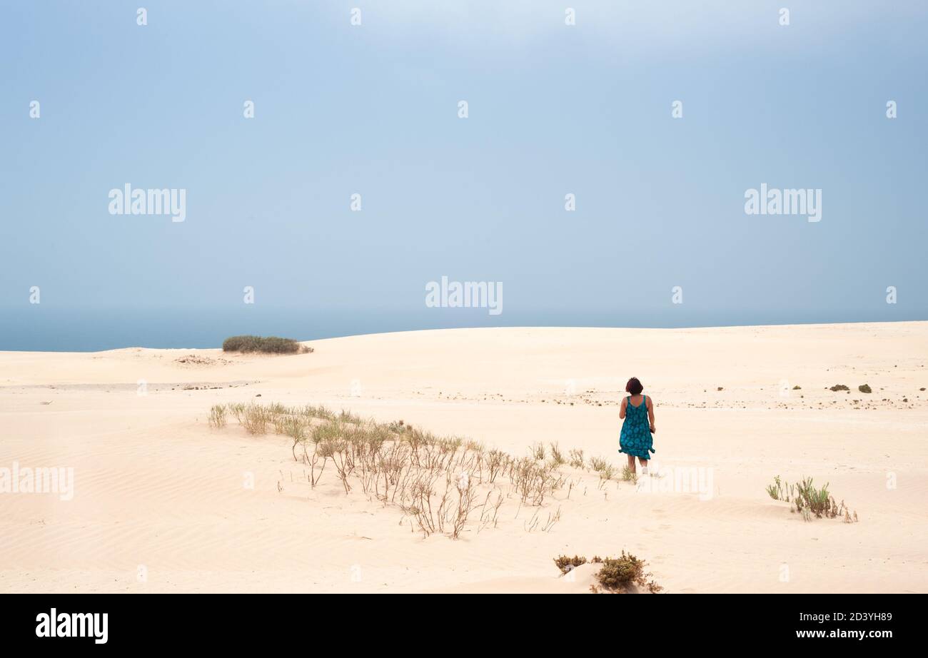 Jeune femme marchant à travers les champs de sable et colline vers l'Atlantique Océan dans le parc national de Tamri au Maroc Banque D'Images