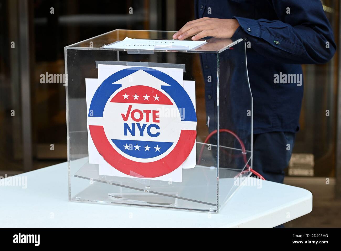 New York, États-Unis. 08 octobre 2020. Un greffier se tient à côté d'une boîte en plexiglas où les personnes s'inscrivant pour voter aux tables installées sur le trottoir à l'extérieur du bureau du quartier de élections Manhattan, à New York, NY, le 8 octobre 2020. (Anthony Behar/Sipa USA) crédit: SIPA USA/Alay Live News Banque D'Images