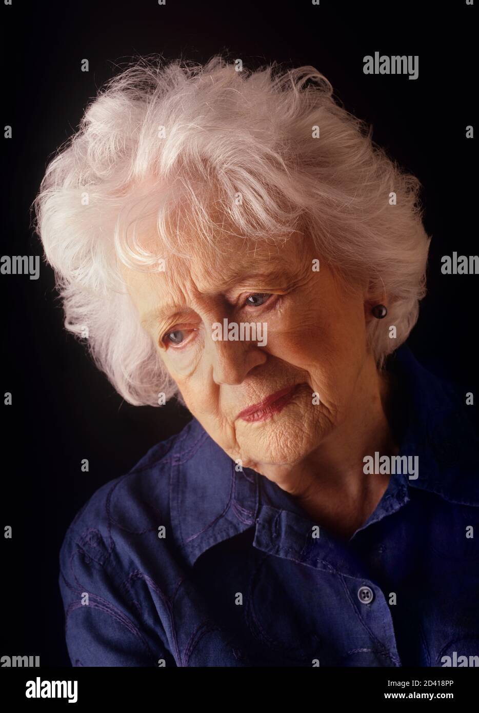 Femmes âgées déprimées regardant vers le bas isolées sur fond noir Banque D'Images