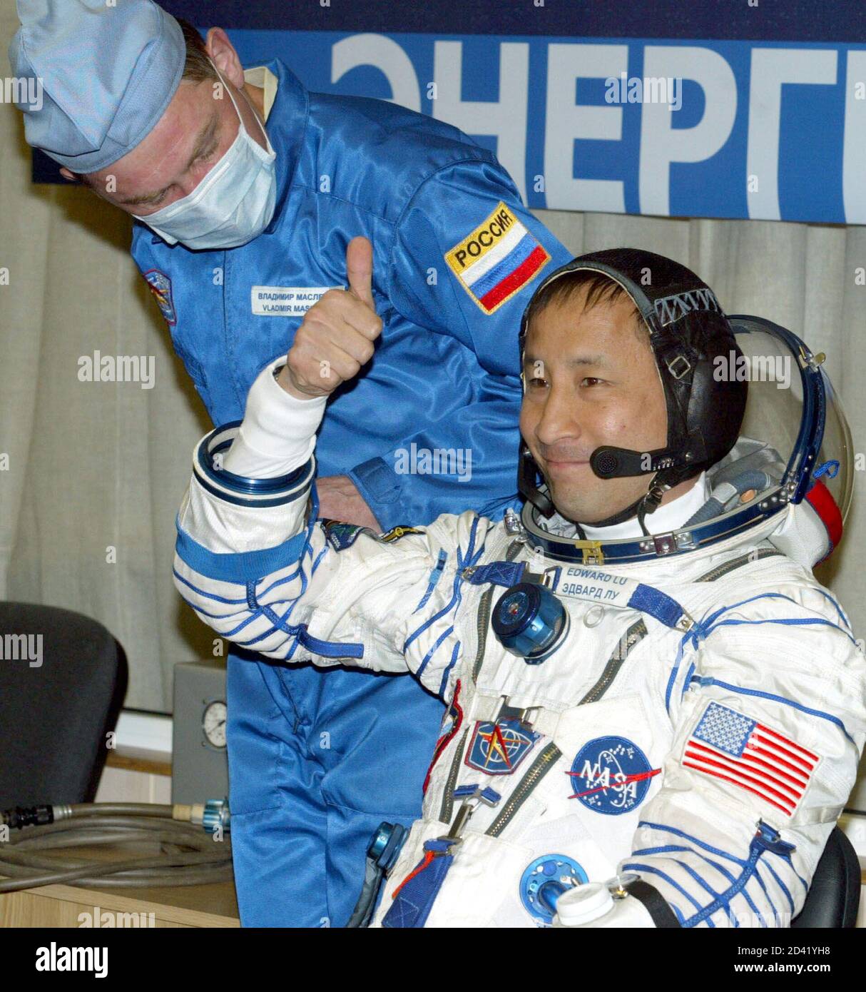 U.S. astronaut Edward Lu gives a thumbs up as a Russian specialist stands  by after dressing up in his space suit in Baikonur, April 26, 2003. [Lu and  Russian cosmonaut Yuri Malenchenko]