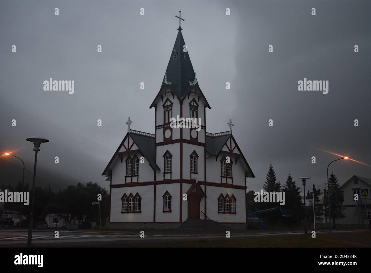 Húsavíkurkirkja, Église en bois de Husavik lors d'une soirée brumeuse et brumeuse dans la baie de Skjalfandi, au nord-est de l'Islande. Les réverbères s'allument en orange par temps effrayant. Banque D'Images