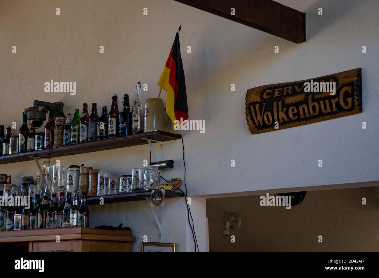 Le mur décoré de la salle à manger de la brasserie Wolkenburg avec quelques bouteilles de bière sur les étagères avec le drapeau allemand et une assiette en bois. Banque D'Images
