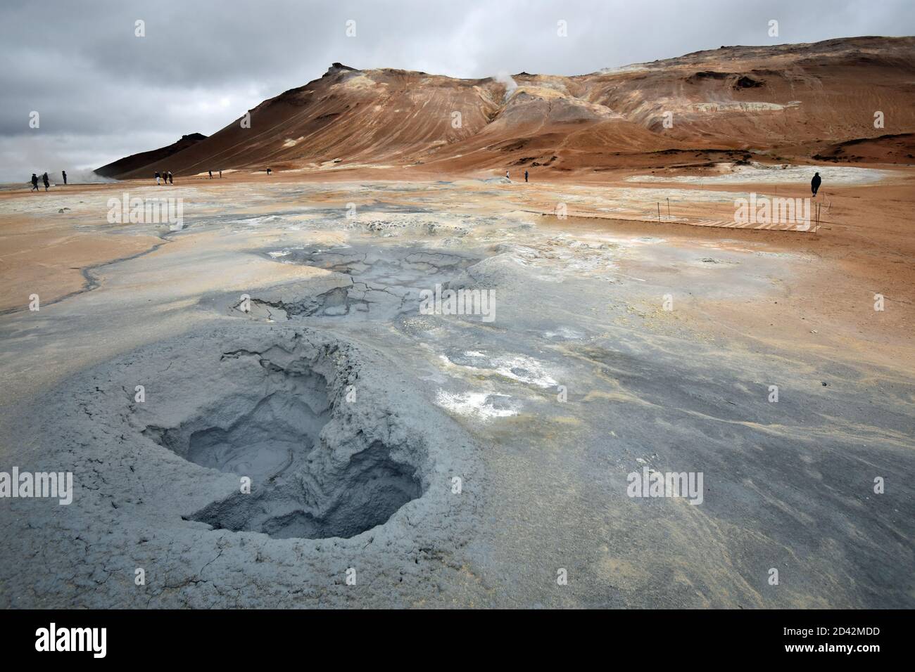 Montagne Námafjall et zone géothermique de Hverir près du lac Myvatn dans le nord de l'Islande. Les visiteurs marchent parmi les piscines de boue grise et d'ébullition et le paysage orange. Banque D'Images