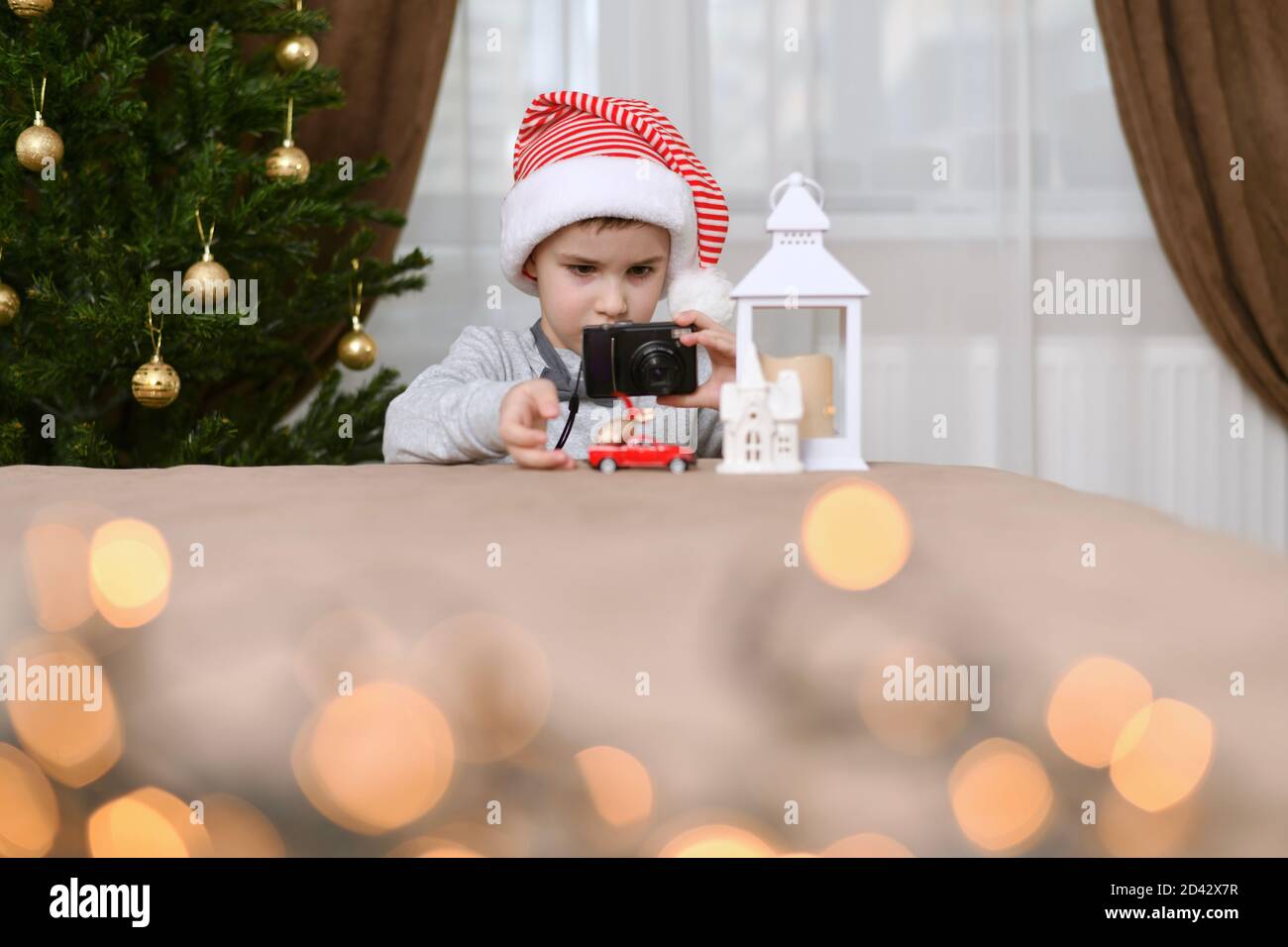 Attention, enfant focalisé sur la machine corrige la poussée de la main dans la maison. Regarde dans la caméra. Près de l'arbre de Noël. Banque D'Images