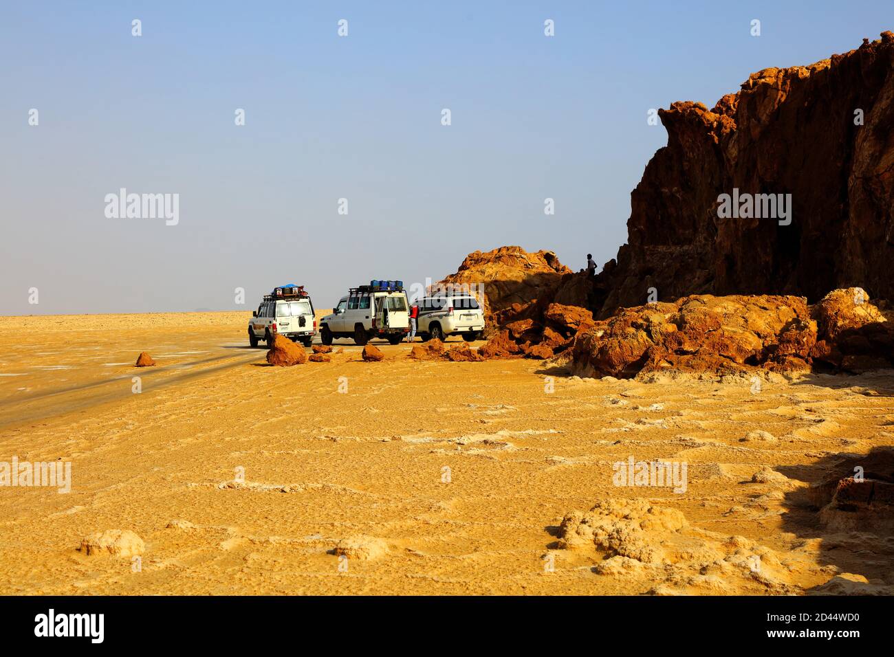 Les véhicules à quatre roues motrices sont garés à côté d'un affleurement rocheux sur les plates-forme salées de la dépression de Danakil sous un ciel bleu pâle à Hamadella, en Éthiopien Banque D'Images