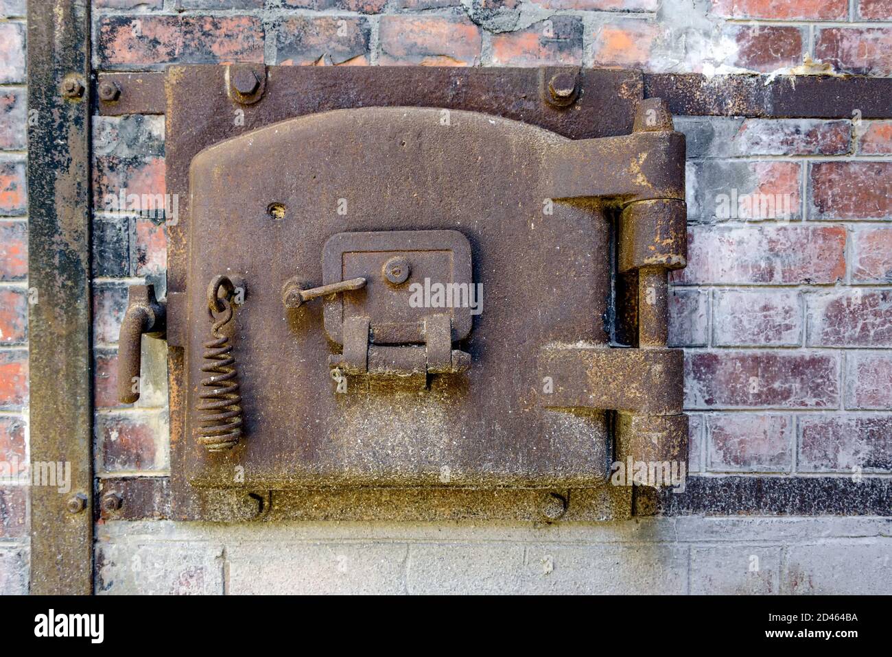 Vieux portillon en métal rouillé d'un four en brique rouge dans une usine abandonnée. Porte d'accès en métal rouillé avec cadre en métal boulonné à l'ancien mur en brique rouge. Banque D'Images