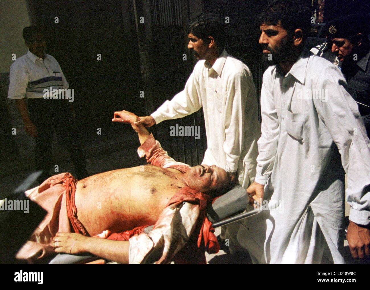 Des personnes retirent un corps à la suite d'un incident de tir à Lahore le 19 mars 2002. Deux hommes armés non identifiés sur une moto ont tué mardi un professeur, son chauffeur et un passant dans la province centrale de Pujab, au Pakistan, dans deux incidents distincts, a déclaré la police. REUTERS/Mohsin Raza ZH/CP Banque D'Images