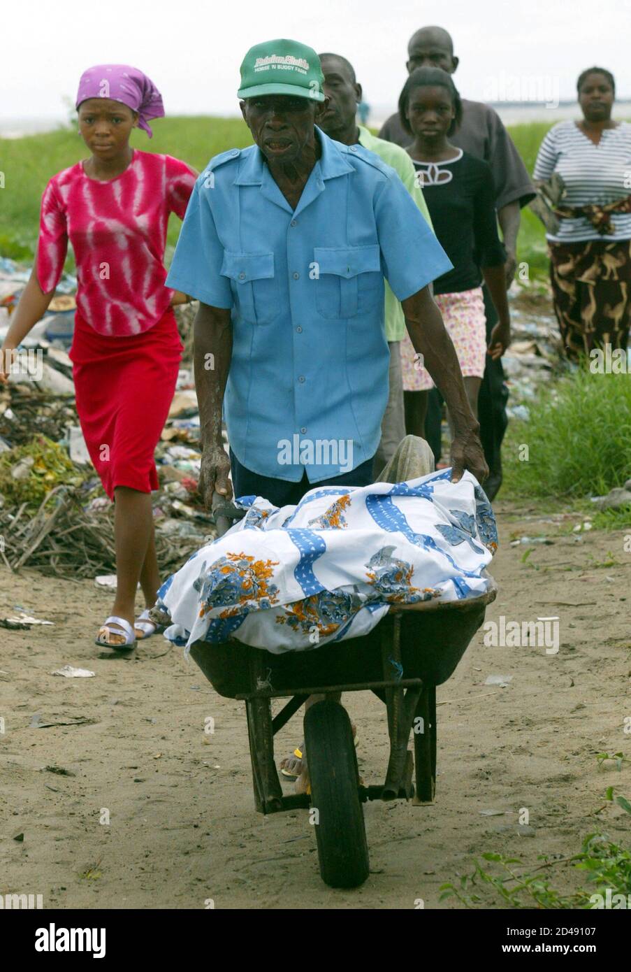 Liberians relatives carry a body in a wheelbarrow after the elderly woman  was hit in the head by a bullet while she was putting rubbish into the sea  off West Point, Monrovia