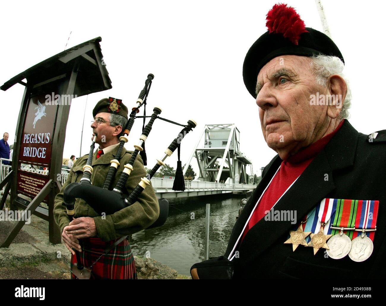 D-Day Allied landings veteran Joe Womersley (R), a British-born Canadian,  listens as Canadian Charles Meanwell (L) plays 'Amazing Grace' on the  bagpipes in front of the Pegasus Bridge in Benouville, northern France,