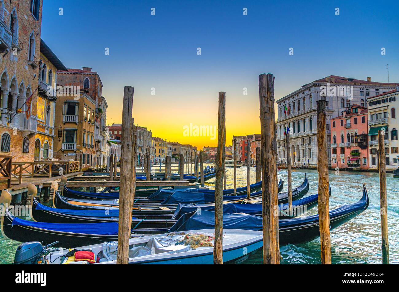 Gondoles amarrées sur l'embarcadère de la voie navigable du Grand Canal à Venise. Poteaux en bois et bâtiments de style baroque le long du Canal Grande. Paysage urbain incroyable à Venise au crépuscule. Vénétie, Italie Banque D'Images