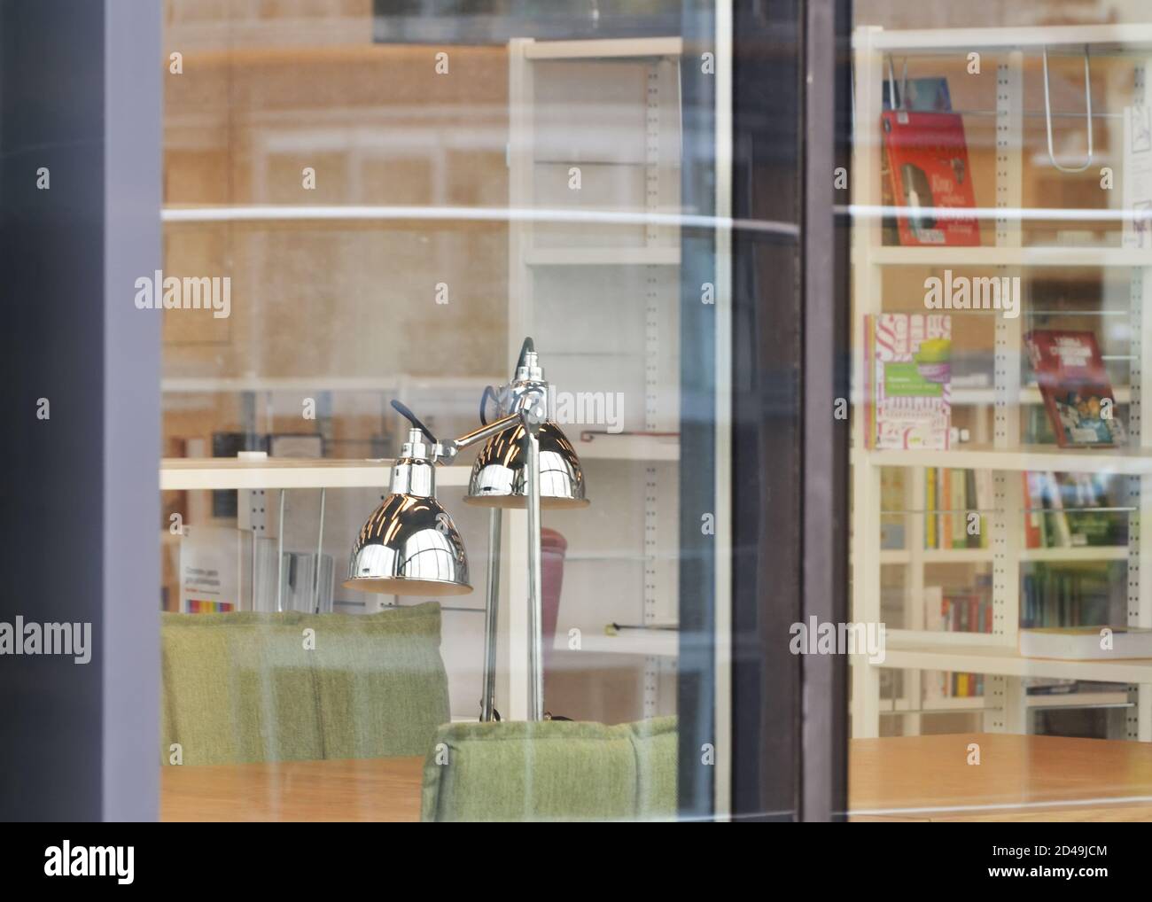 Une lampe de table argentée sur une table de la bibliothèque. Vue à travers la vitre. Banque D'Images