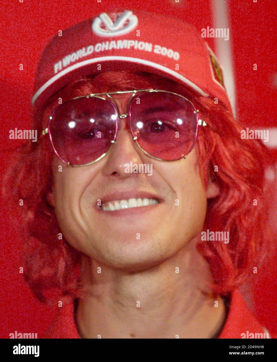 Michael Schumacher, champion du monde de Formule 1, porte une casquette de  champion du monde, une perruque de couleur scarlet pour son équipe Ferrari  et des lunettes de couleur rose lors d'une