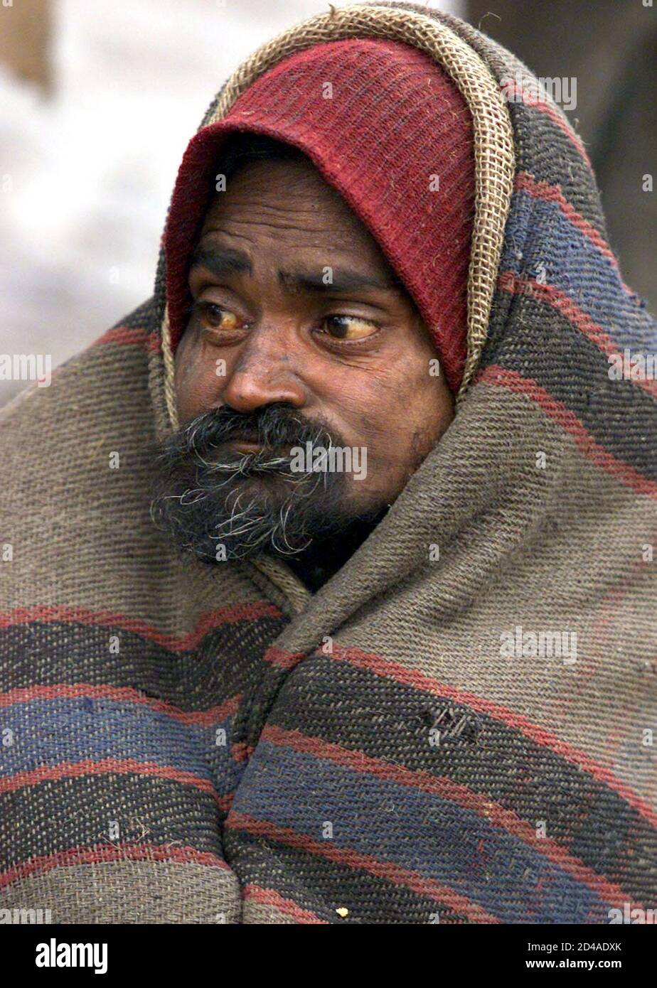 Un cheller indien de taudis utilise une couverture pour se maintenir au chaud lors d'une matinée froide à New Delhi le 18 janvier 2003. Le nombre de morts a atteint 1,100 vendredi dans un climat froid qui a blanchi l'Asie du Sud avec du gel et du brouillard et a paralysé la circulation aérienne, routière et ferroviaire. REUTERS/Kamal Kishore JSG/FA Banque D'Images