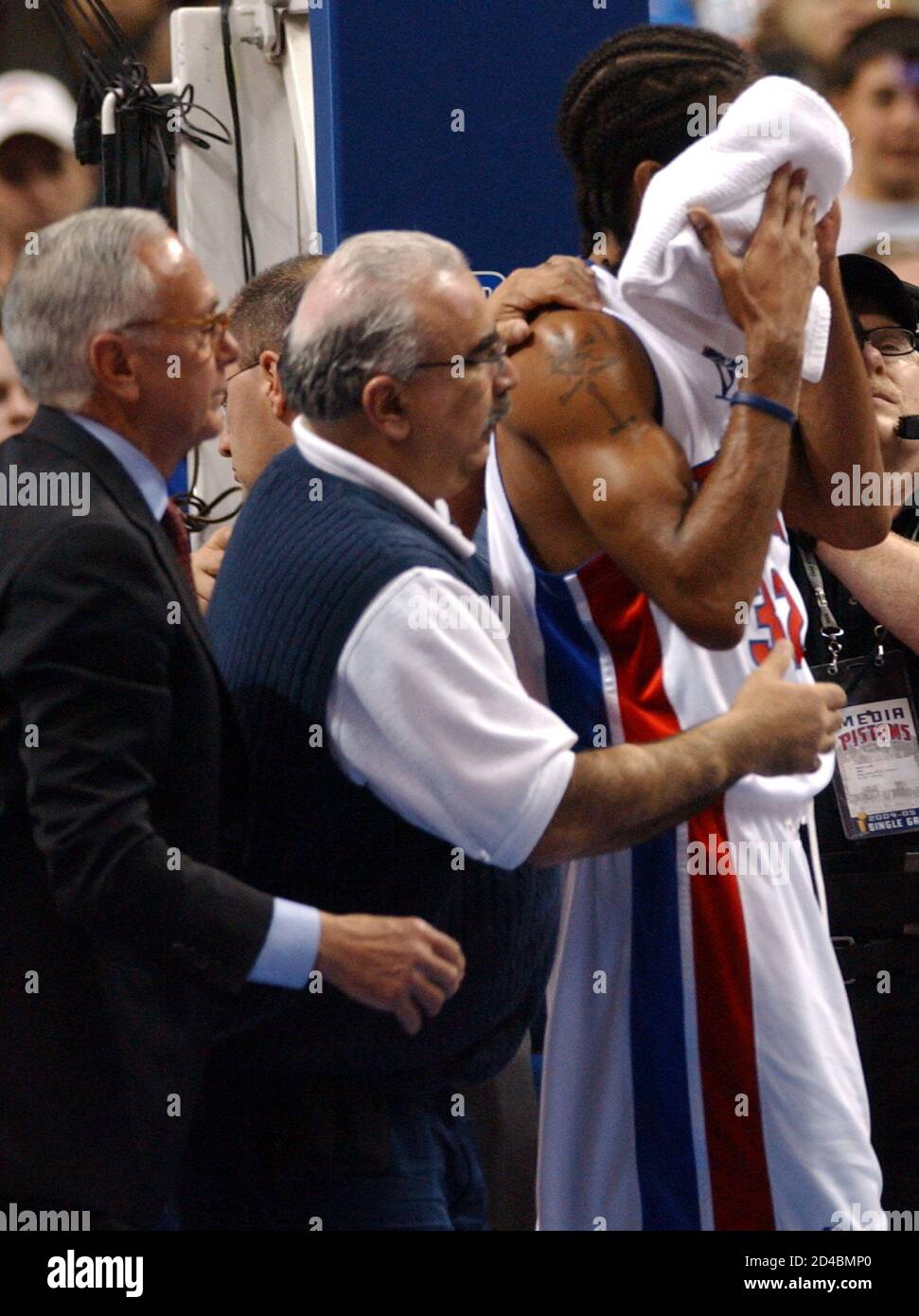 Detroit Pistons guard Richard Hamilton (R) holds a towel to his face as  he's escorted off the court by Piston's trainer Mike Abdenour (C) and head  coach Larry Brown (L) after being