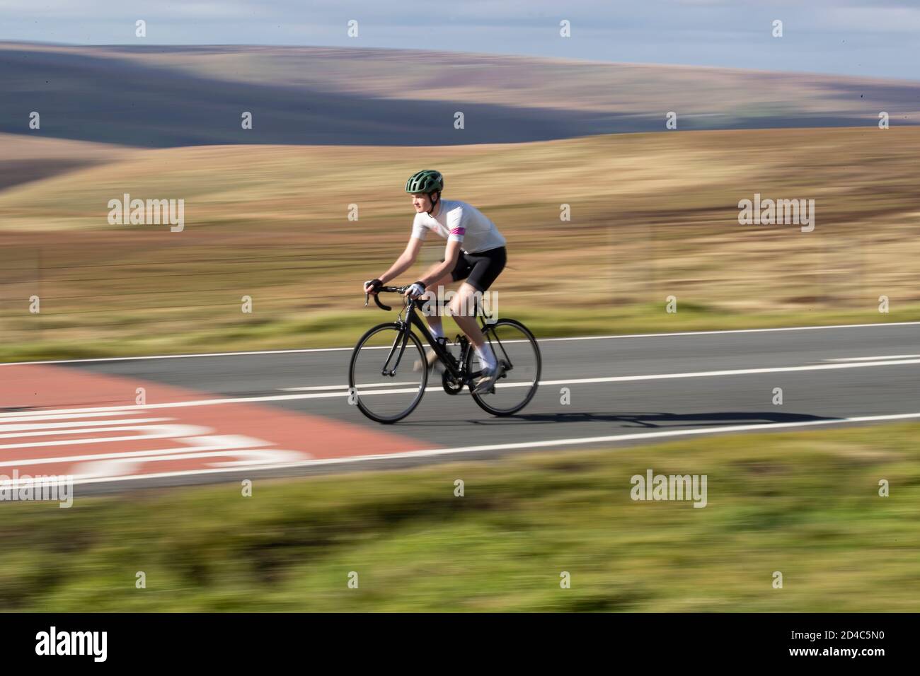 Jeune cycliste roulant à grande vitesse sur les hautes terres de The Yorkshire Moors at Wessenden Head avec un arrière-plan flou de mouvement Banque D'Images