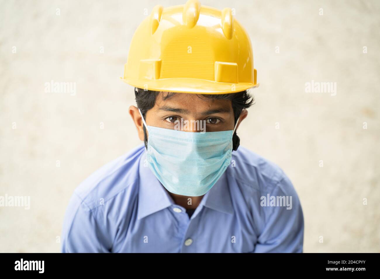 Vue en grand angle du travailleur de la construction dans le masque médical regardant en confiance - concept de l'entreprise, l'industrie rouvre et Covid-19 mesures de sécurité à Banque D'Images