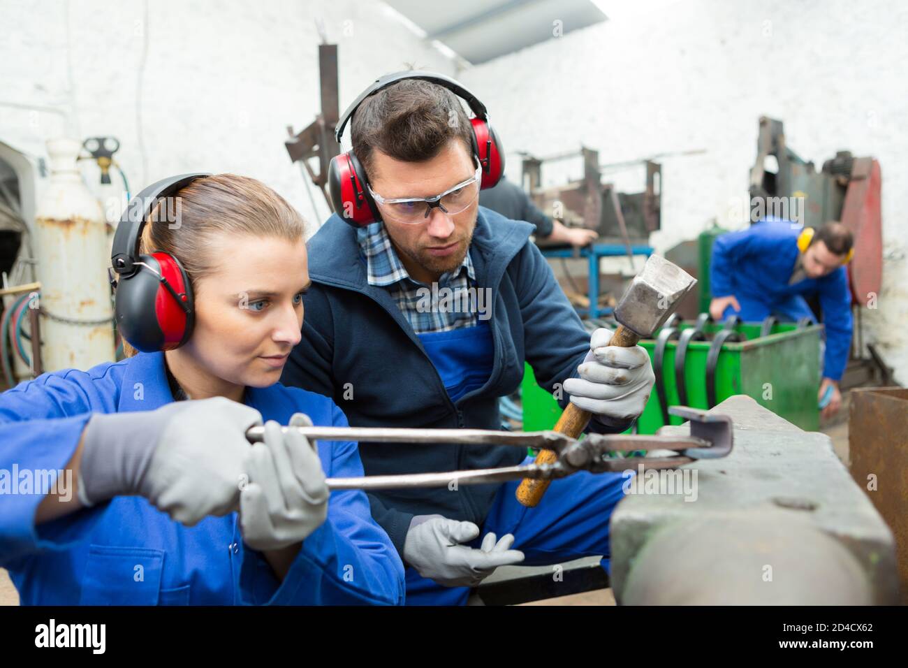 femme tenant le métal sur l'enclume avec des pinces Banque D'Images