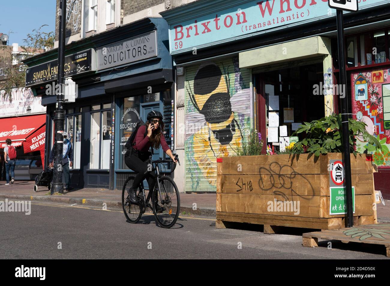 Une cycliste féminine utilisant un téléphone portable tout en faisant un vélo sur la fermeture de la route Atlantique le 16 septembre 2020 à Brixton au Royaume-Uni. P Banque D'Images