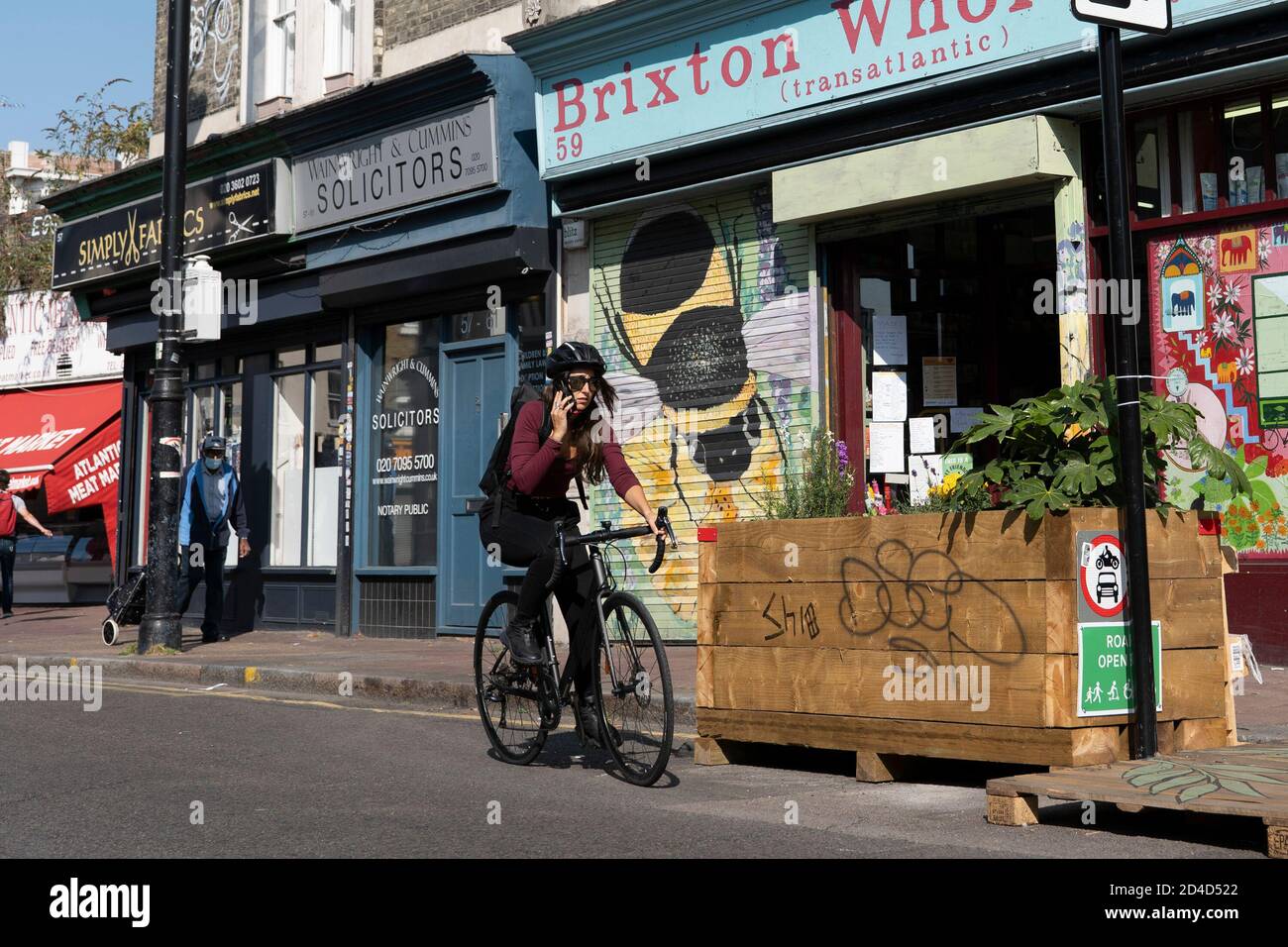 Une cycliste féminine utilisant un téléphone portable tout en faisant un vélo sur la fermeture de la route Atlantique le 16 septembre 2020 à Brixton au Royaume-Uni. P Banque D'Images