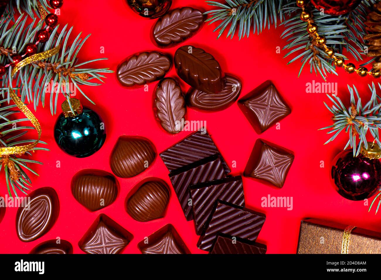 Chocolats sur fond rouge. Décoration et chocolat du nouvel an 2021, bonbons - photo de fête pour la confiserie. Banque D'Images