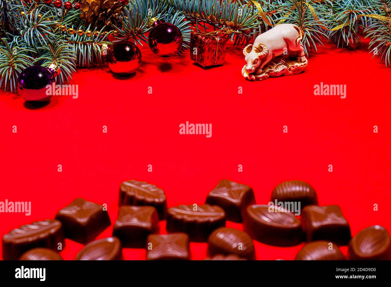 Des chocolats sur fond rouge ensorvés un taureau. Nouveau-an 2021 décor et chocolat, bonbons - photo de fête pour la confiserie avec place pour le texte Banque D'Images