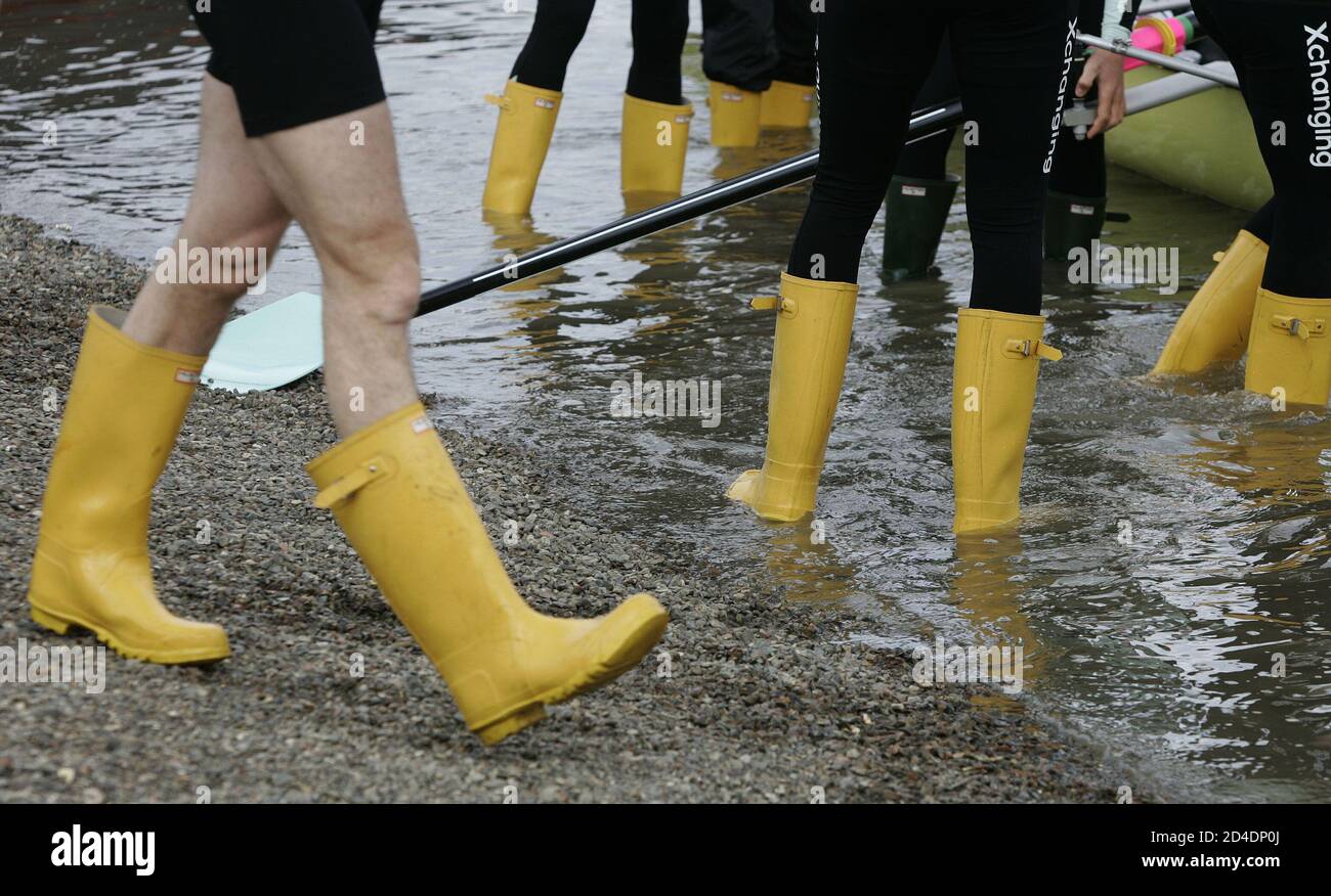 Crew members of the Cambride University Boat race team wear yellow  wellington boots as they ready their boat prior to training on the River  Thames in London. Crew members of the Cambridge