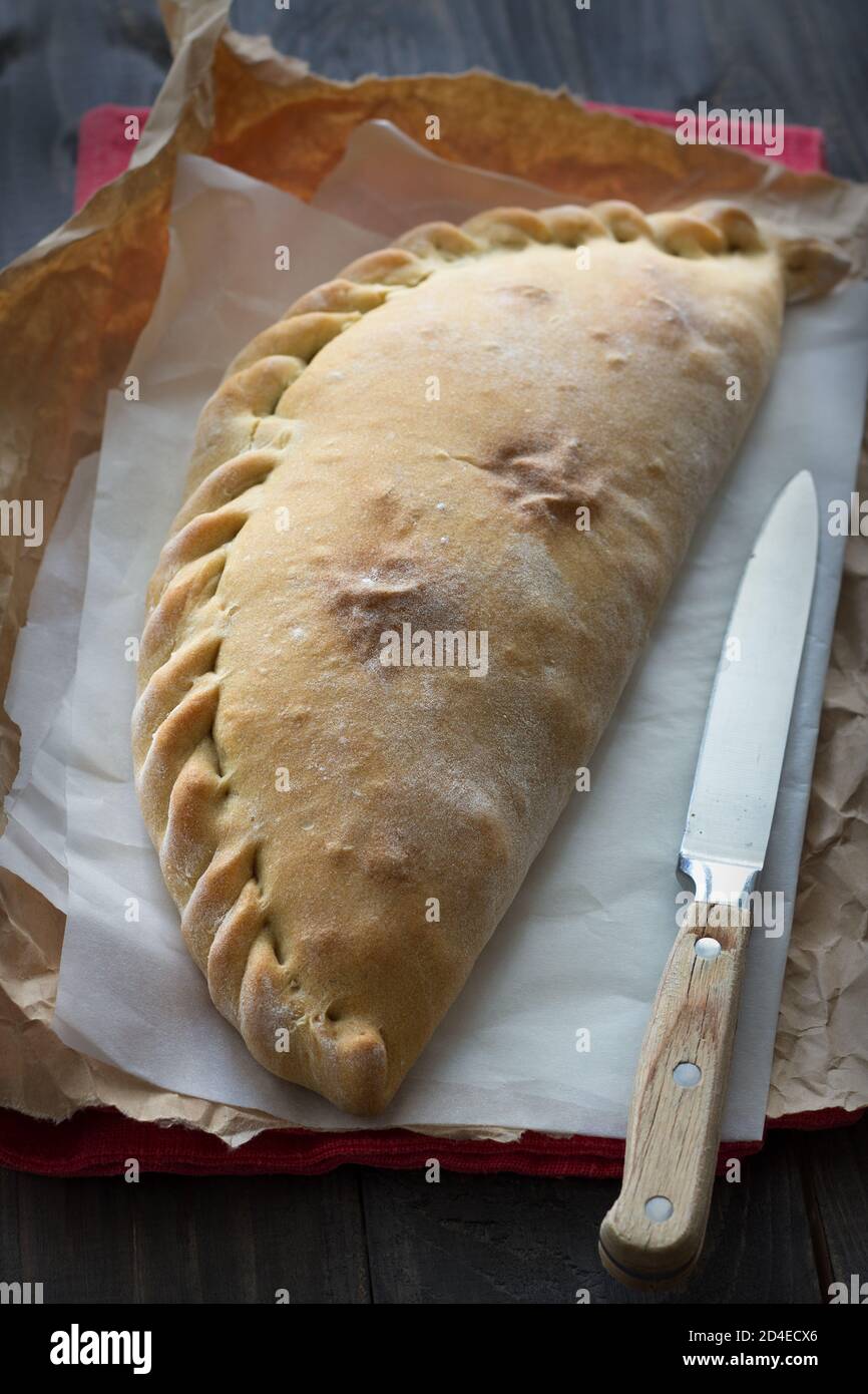 Pizza italienne calzone aux champignons, épinards et fromage sur une surface en bois, style rustique, sélectif Banque D'Images