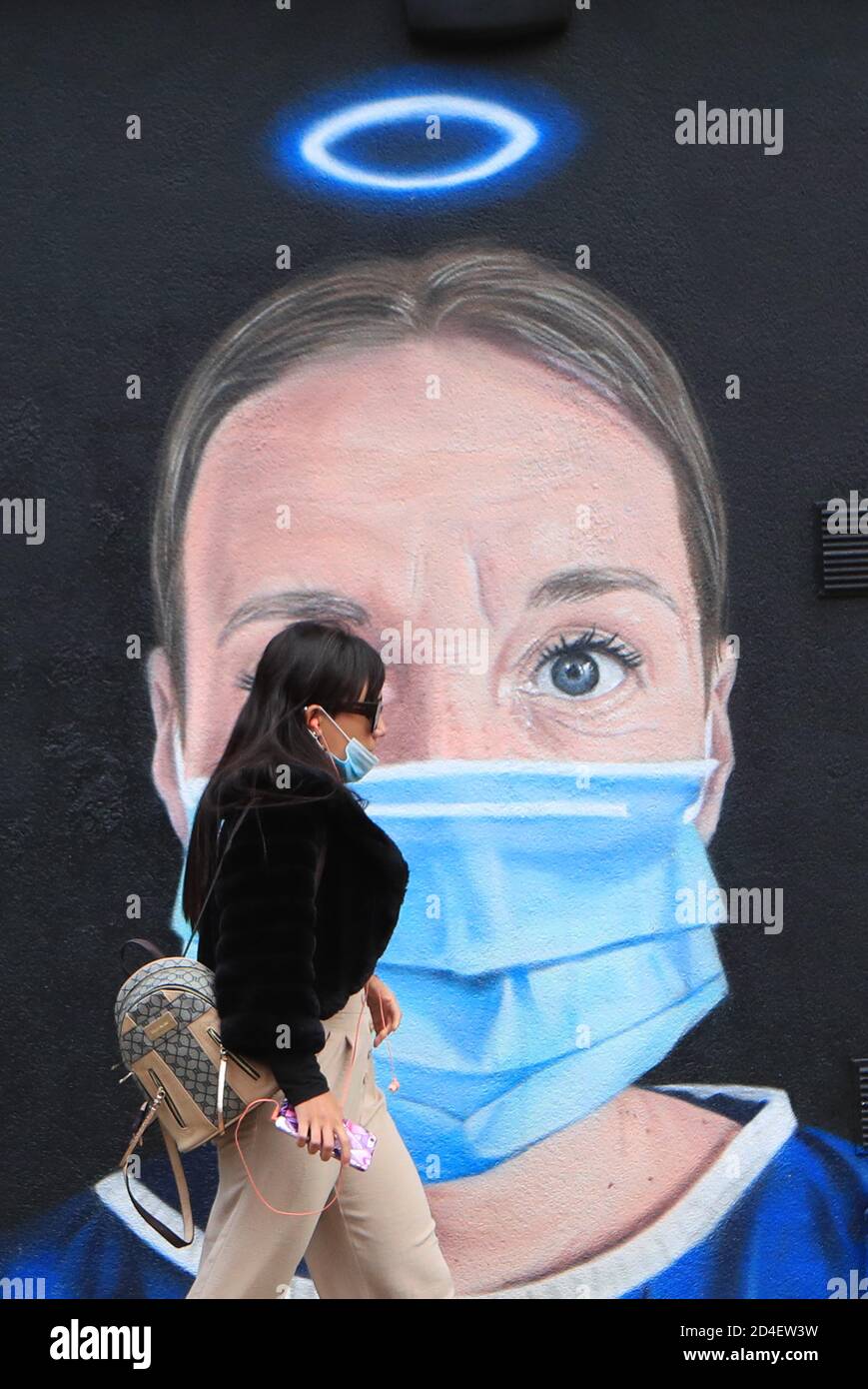 Une femme passe devant une fresque dans le centre-ville de Manchester. Dans les villes du nord de l'Angleterre et dans d'autres régions qui souffrent d'une augmentation des cas de Covid-19, les pubs et les restaurants peuvent être temporairement fermés pour lutter contre la propagation du virus. Banque D'Images