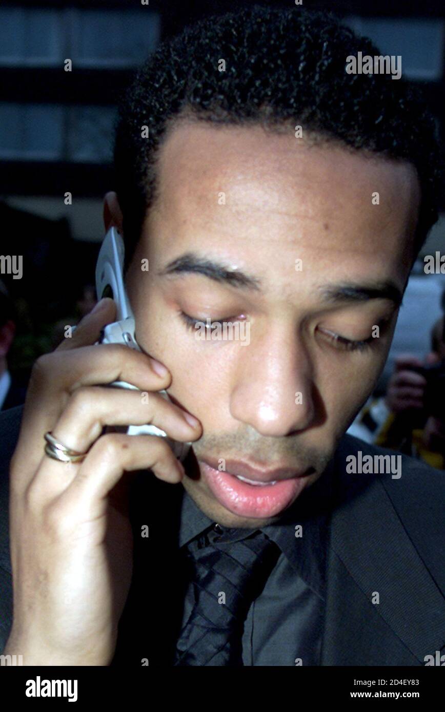 Arsenal's French striker Thierry Henry chats on his mobile telephone as he  leaves his diciplinary hearing in London March 6, 2002. [Henry received a  three game ban after being found guilty of