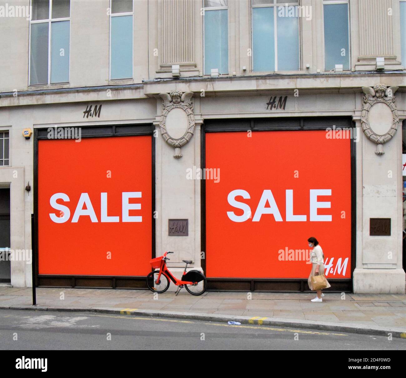 Une femme avec un masque facial protecteur passe devant une grande affiche  rouge solde à l'extérieur du magasin H&M d'Oxford Street, 2020 Photo Stock  - Alamy