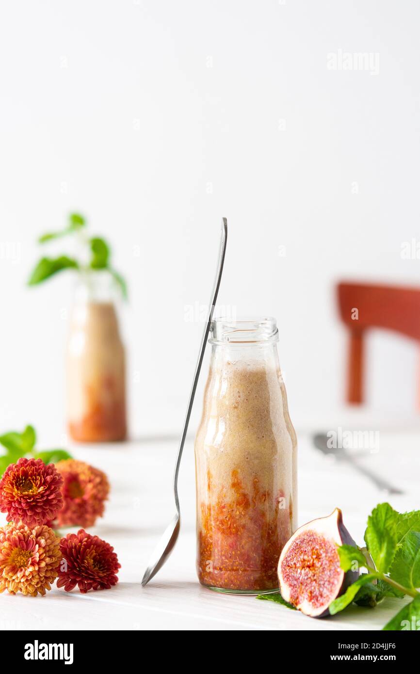 Délicieux smoothie de fruits frais et sains dans des pots en verre, figue au melon et à la banane, fleurs de chrysanthème d'automne à la menthe Banque D'Images