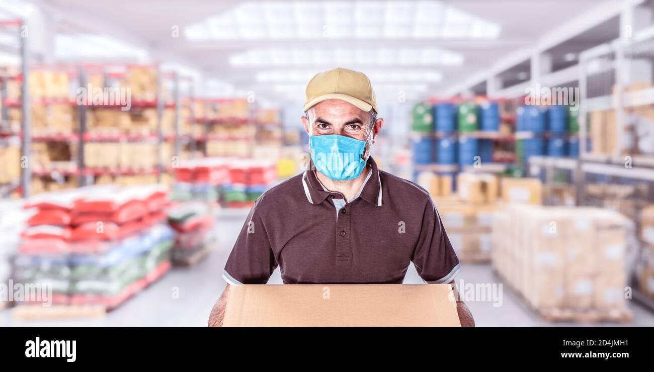 travailleur avec masque dans un entrepôt plein de marchandises Banque D'Images